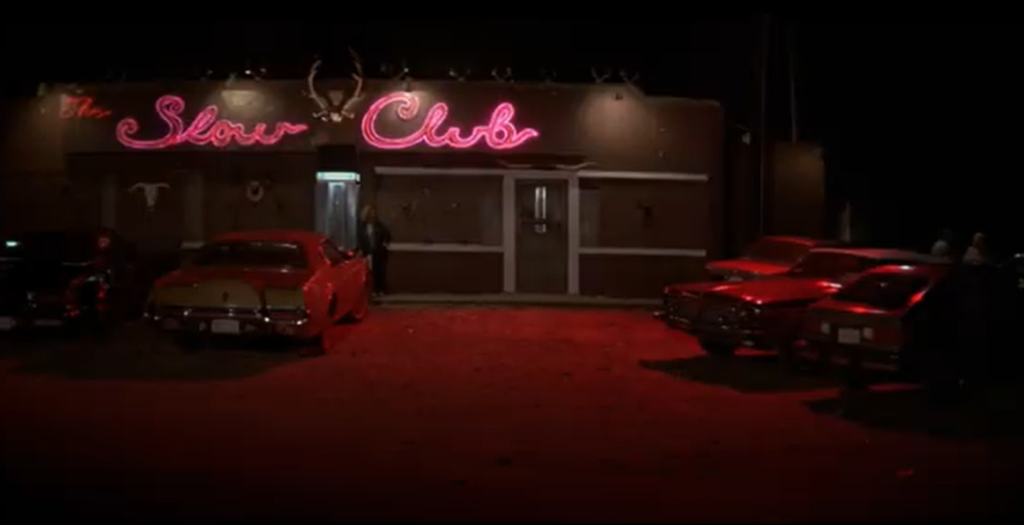 Façade du Slow Club éclairée par des néons rouges, lieu emblématique de Blue Velvet où Dorothy Vallens chante dans une atmosphère feutrée et inquiétante.